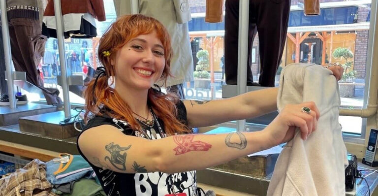 Buffalo Exchange employee holding up an article of clothing