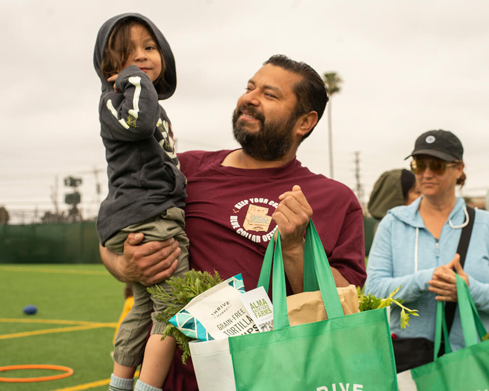 father holding child and bag of food