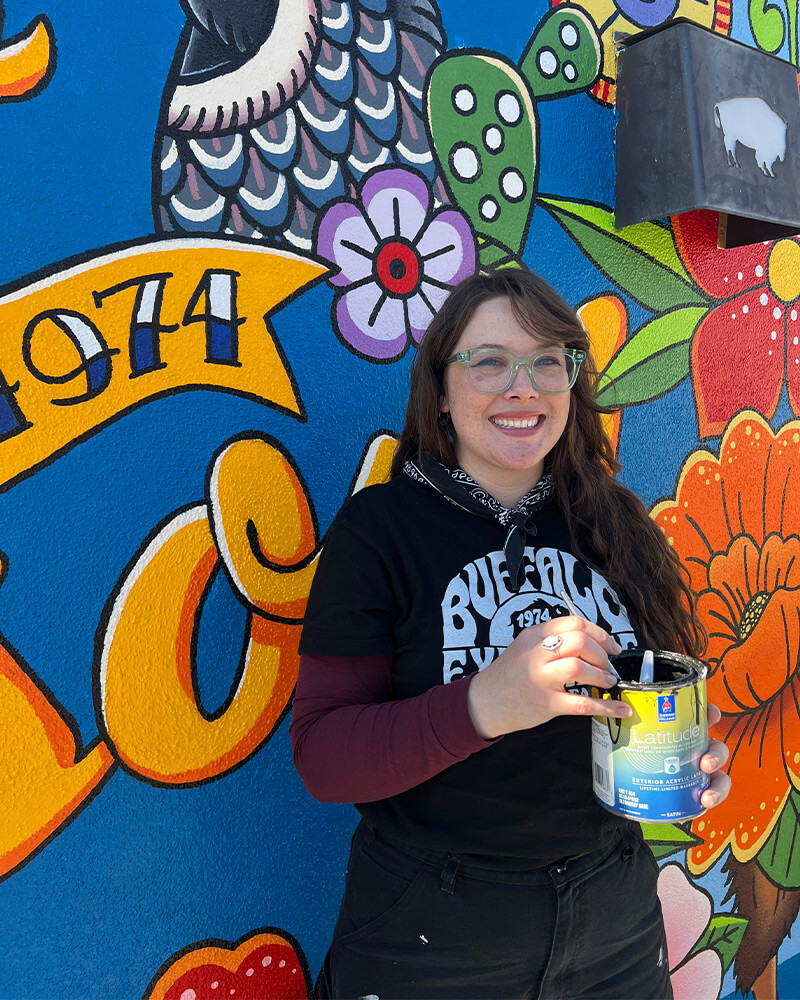emma standing in front of the mural